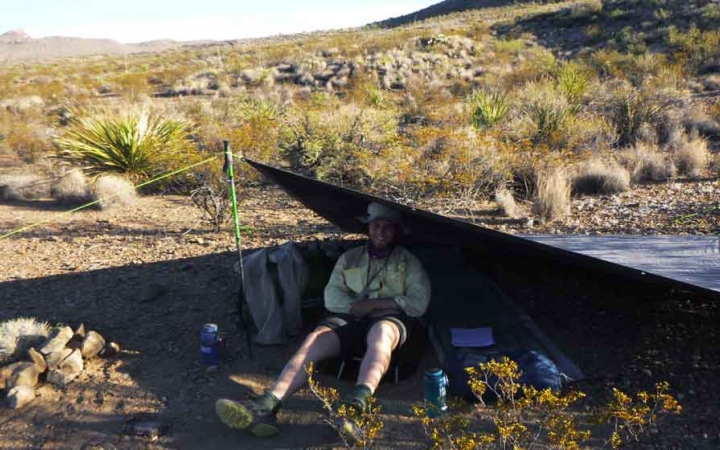a student sits inside their tarp shelter in the desert